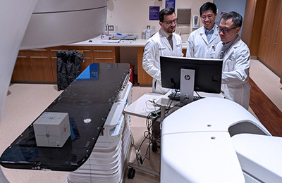Study authors Drs. Mohamed Abazeed (left), Yirong Liu and Troy Teo test a prototype AI tool.
